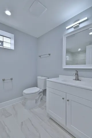 a bathroom with a toilet a sink a mirror and vanity