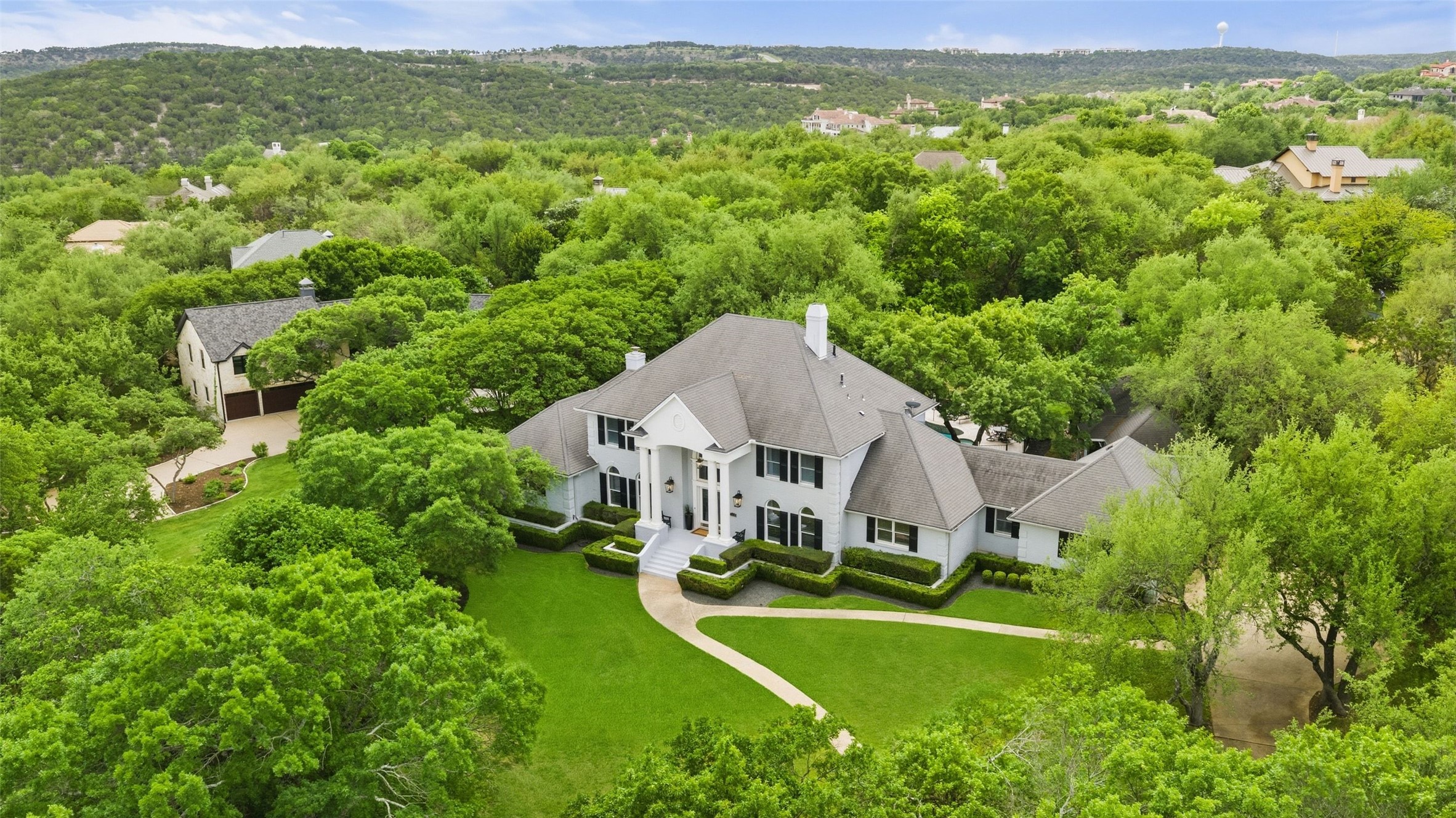White exterior residence featuring a prominent columned portico, dark shutters, and a multi-level roofline