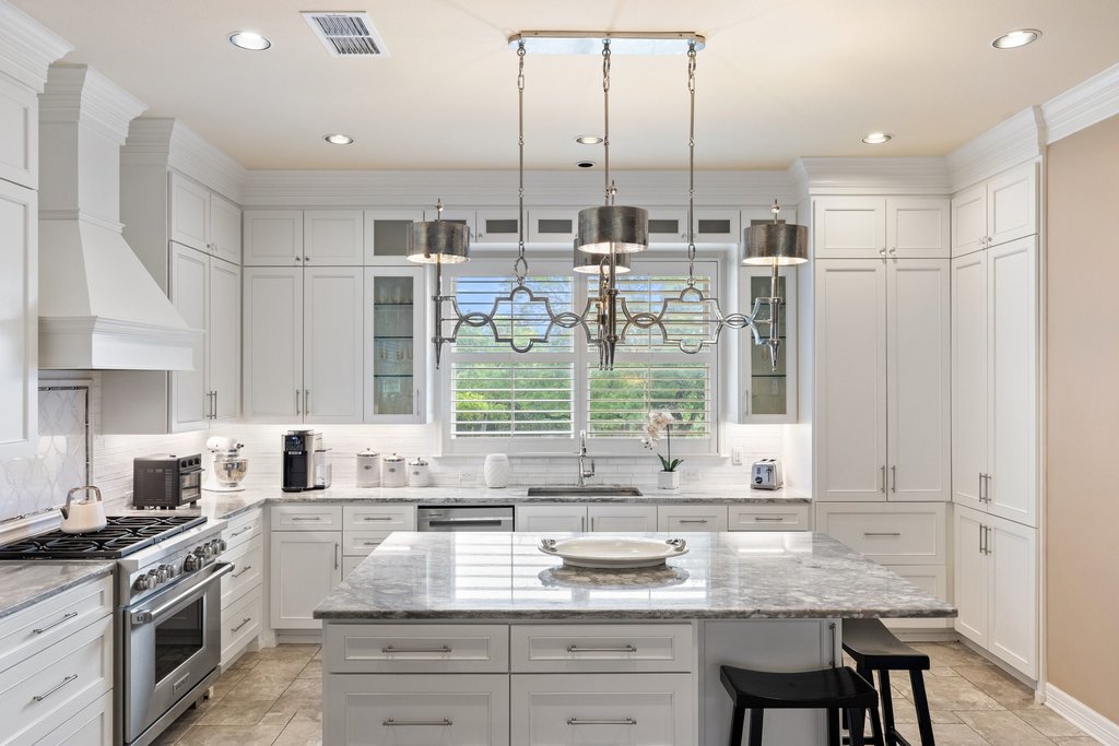7609 Sandia Loop Austin, TX 78735 - Photo 11 of 40 This thoughtfully updated kitchen centers around a massive stone island and professional-grade appliances, all framed by custom white cabinetry and designer pendant lighting.