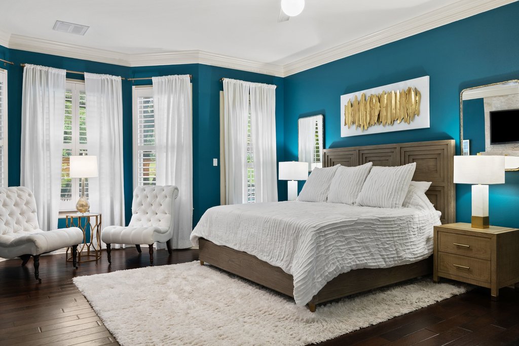 7609 Sandia Loop Austin, TX 78735 - Photo 17 of 40 The primary suite serves as a bold yet sophisticated retreat, anchored by deep jewel tones, rich wood flooring, and a large bay window that provides a bright, private seating area.