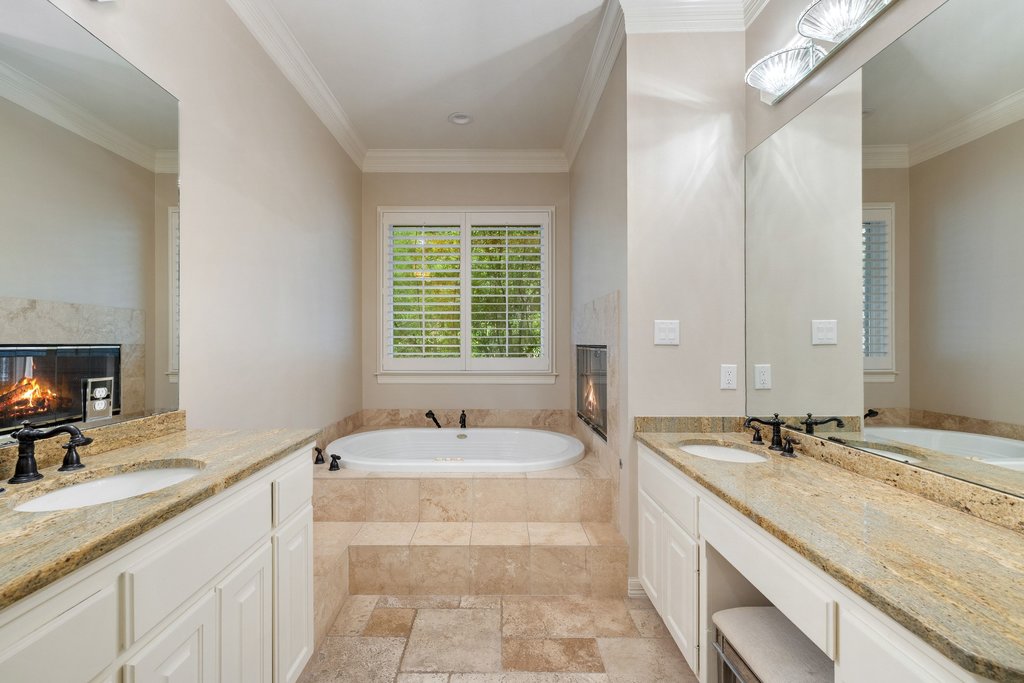 7609 Sandia Loop Austin, TX 78735 - Photo 19 of 40 The expansive primary bathroom offers a spa-like atmosphere with separate vanities, a deep soaking tub, and a double-sided fireplace that adds warmth and luxury to the space.