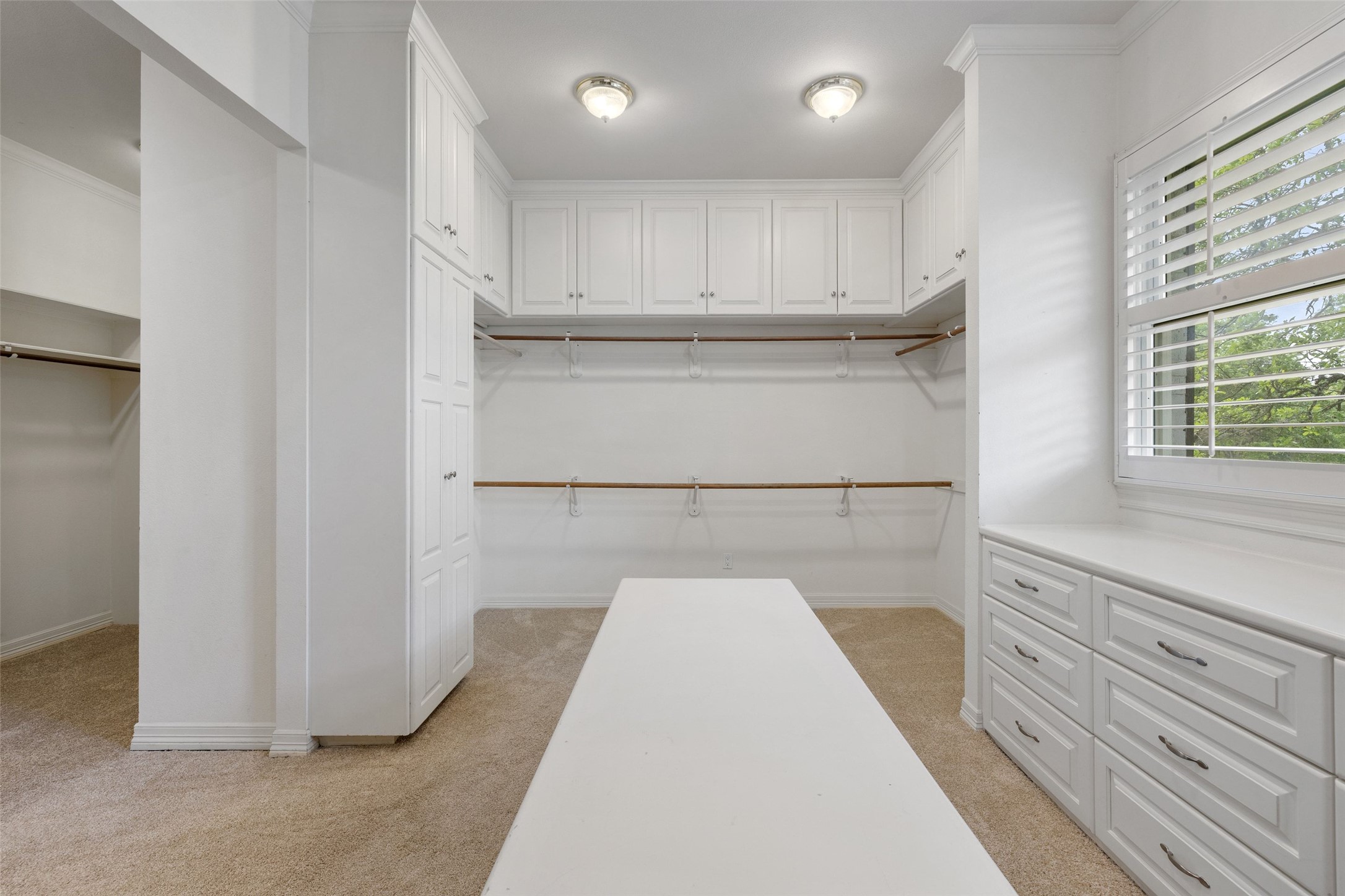 7609 Sandia Loop Austin, TX 78735 - Photo 22 of 40 Spacious walk-in closet featuring extensive built-in cabinetry, an integrated central island, multiple hanging rods, recessed lighting, and a large window with plantation shutters