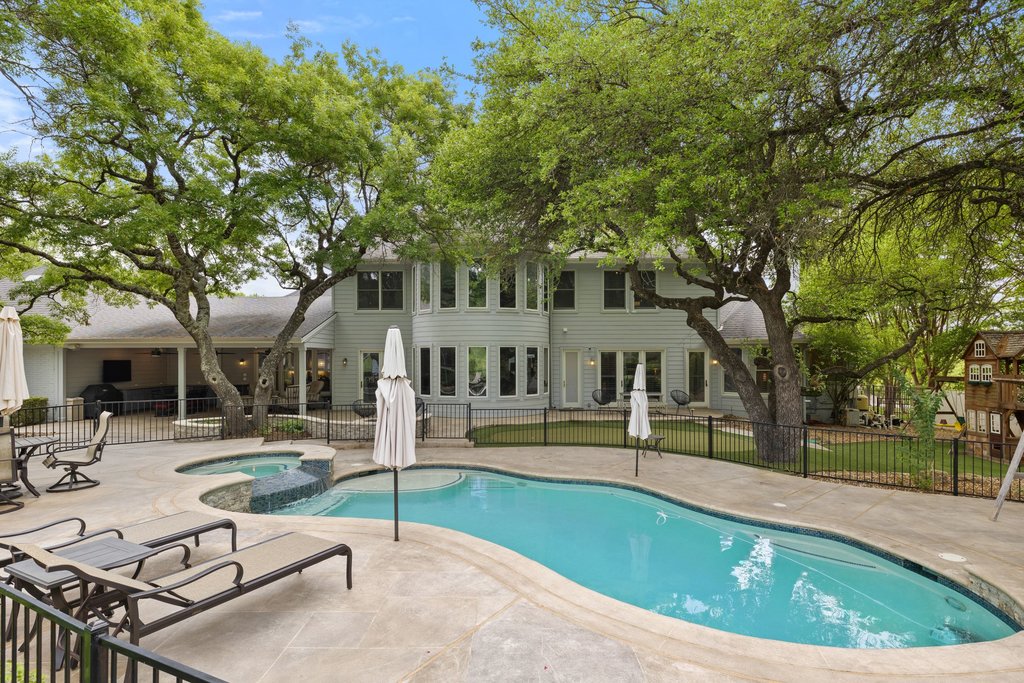 7609 Sandia Loop Austin, TX 78735 - Photo 28 of 40 The backyard is a true resort-style escape, featuring a sparkling pool and spa set against a backdrop of mature oaks and a sprawling lawn that emphasizes the property’s one-acre scale.