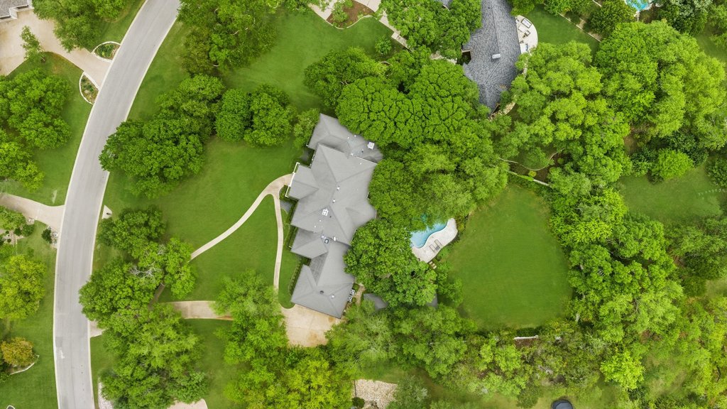7609 Sandia Loop Austin, TX 78735 - Photo 38 of 40 Aerial perspective showcasing a multi-gabled roofline, a curved swimming pool, extensive green lawn areas, mature trees, and a paved driveway with a walkway