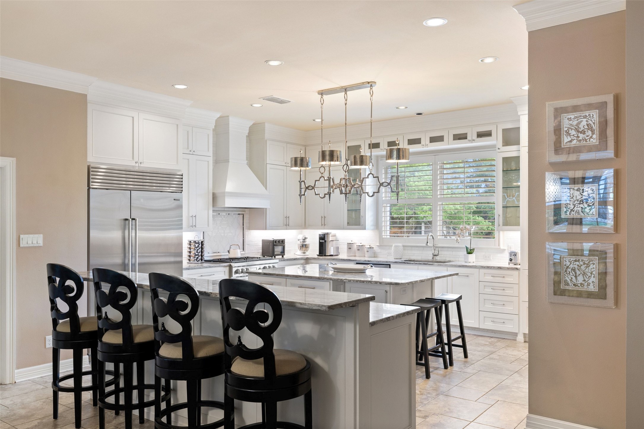 7609 Sandia Loop Austin, TX 78735 - Photo 5 of 40 Spacious kitchen featuring white cabinetry, a large kitchen island with counter seating, stainless steel appliances, and a decorative pendant light fixture
