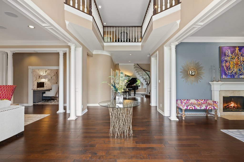 7609 Sandia Loop Austin, TX 78735 - Photo 6 of 40 Grand entryway featuring rich wood-finish flooring, a double-height ceiling, architectural columns, a fireplace with a stone surround, and an open upper-level landing with white balusters