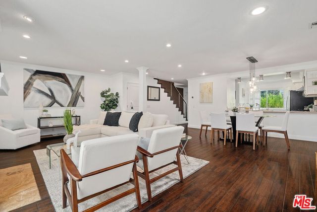 a living room with furniture a wooden floor and next to a window