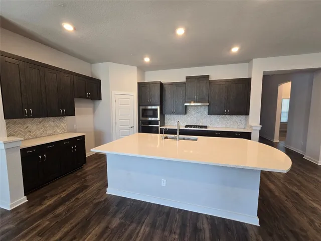 a large kitchen with kitchen island a stove a sink and a refrigerator