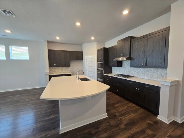 a large kitchen with kitchen island a sink dishwasher a stove and a refrigerator with wooden floor