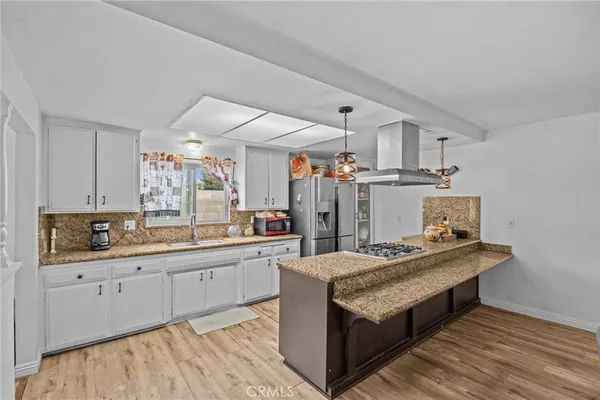 a large kitchen with kitchen island a sink stove and wooden floor