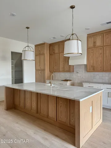 a kitchen with a sink a center island cabinets and a wooden floor