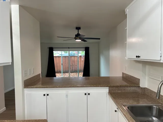 a kitchen with granite countertop a sink and white cabinets