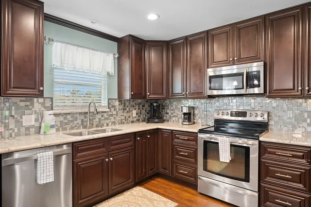 a kitchen with stainless steel appliances granite countertop wooden cabinets a stove top oven a sink and dishwasher