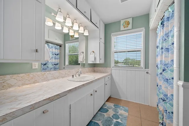 a spacious bathroom with a granite countertop sink a large mirror and a shower