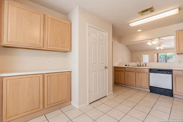 an empty room with chandelier fan and windows