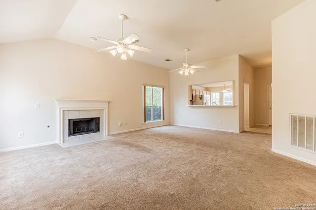 an empty room with a chandelier fan and a table