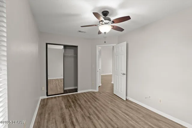an empty room with wooden floor closet and fan