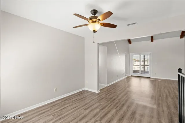 an empty room with wooden floor and ceiling fan