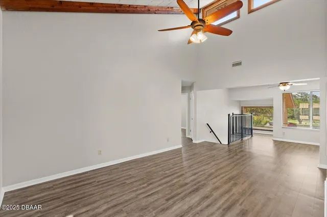 a view of an empty room with window and wooden floor