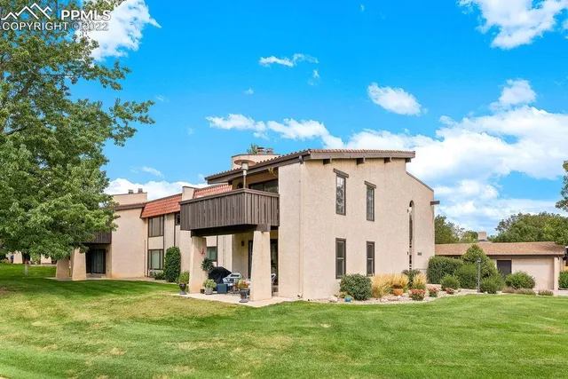 a view of a white house with a big yard and potted plants