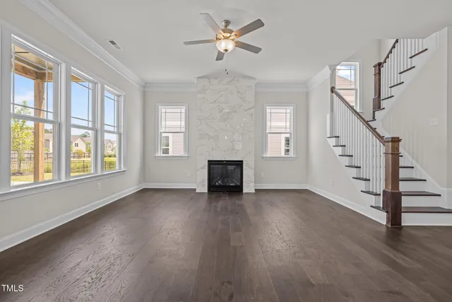 a view of an empty room with wooden floor fireplace and a window
