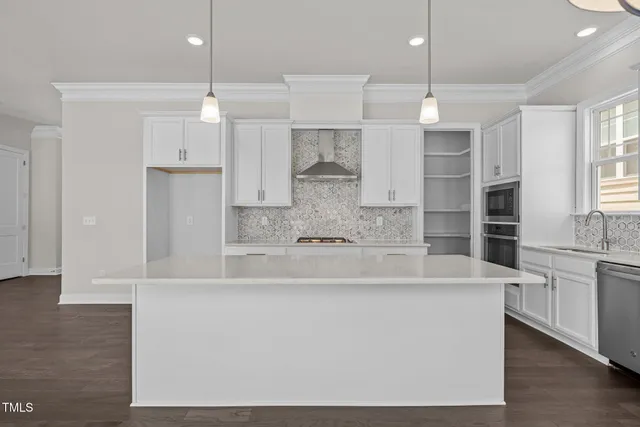 a large white kitchen with kitchen island a sink stainless steel appliances and cabinets