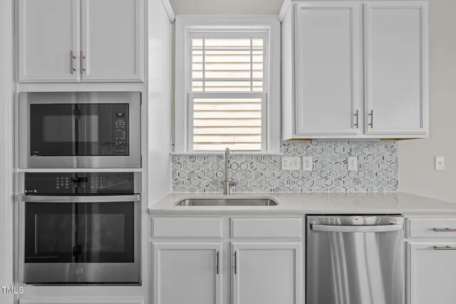 a kitchen with granite countertop white cabinets and stainless steel appliances