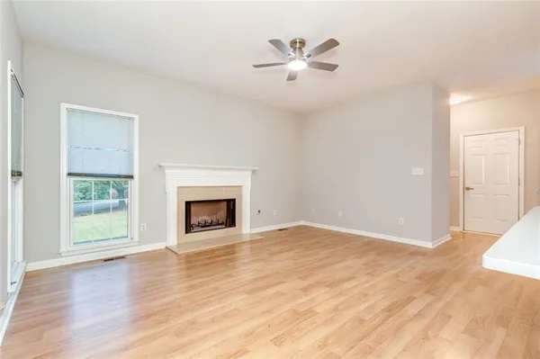 an empty room with wooden floor fireplace and windows