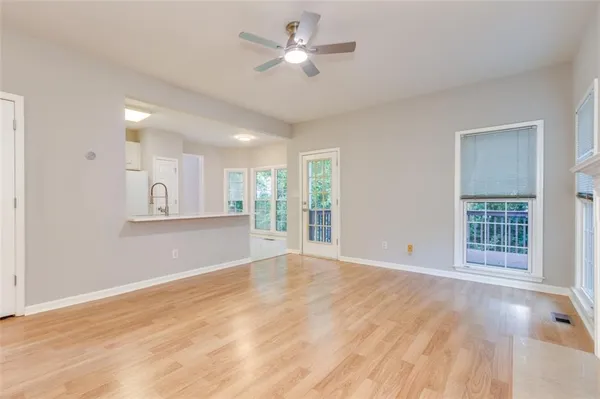a view of an empty room with a window and kitchen view