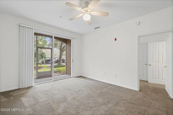 an empty room with chandelier fan and windows