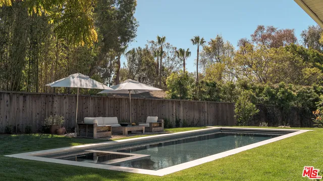 a view of a backyard with swimming pool and sitting area