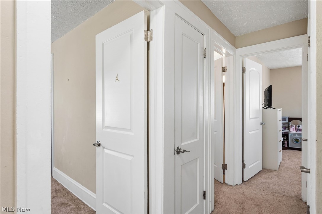 3386 Sylvanhurst Road Cleveland Heights, OH 44112 - Photo 23 of 46 Carpeted hallway featuring multiple white paneled doors with chrome hardware and neutral wall tones