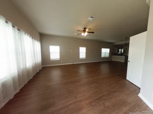 a view of an empty room with window and wooden floor