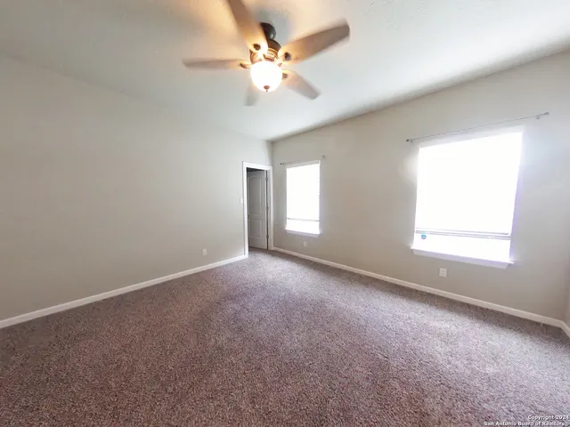 an empty room with windows and chandelier fan
