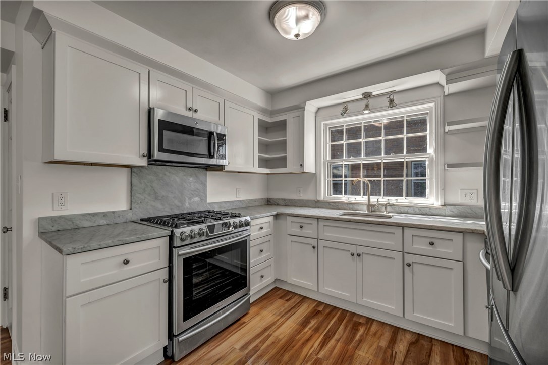 3543 Lytle Road Shaker Heights, OH 44122 - Photo 18 of 49 Kitchen featuring white shaker cabinetry, stainless steel appliances, light gray countertops, a matching backsplash, and wood-finish flooring