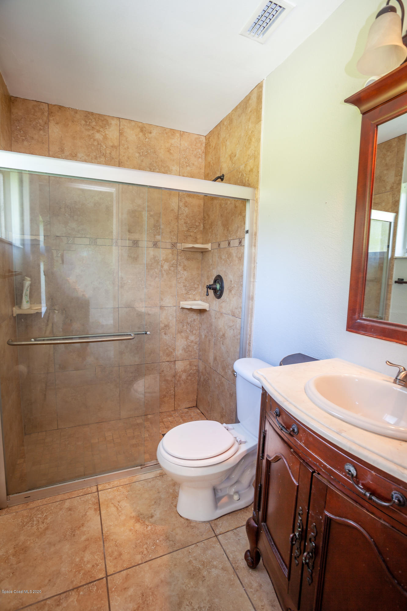 1280 Freil Road Northeast Palm Bay, FL 32905 - Photo 11 of 15 a bathroom with a granite countertop sink a toilet a mirror and shower