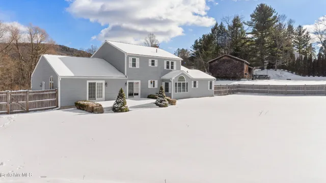 a view of a white house with a yard covered in snow