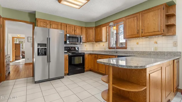 a kitchen with stainless steel appliances granite countertop a refrigerator a sink a stove and cabinets