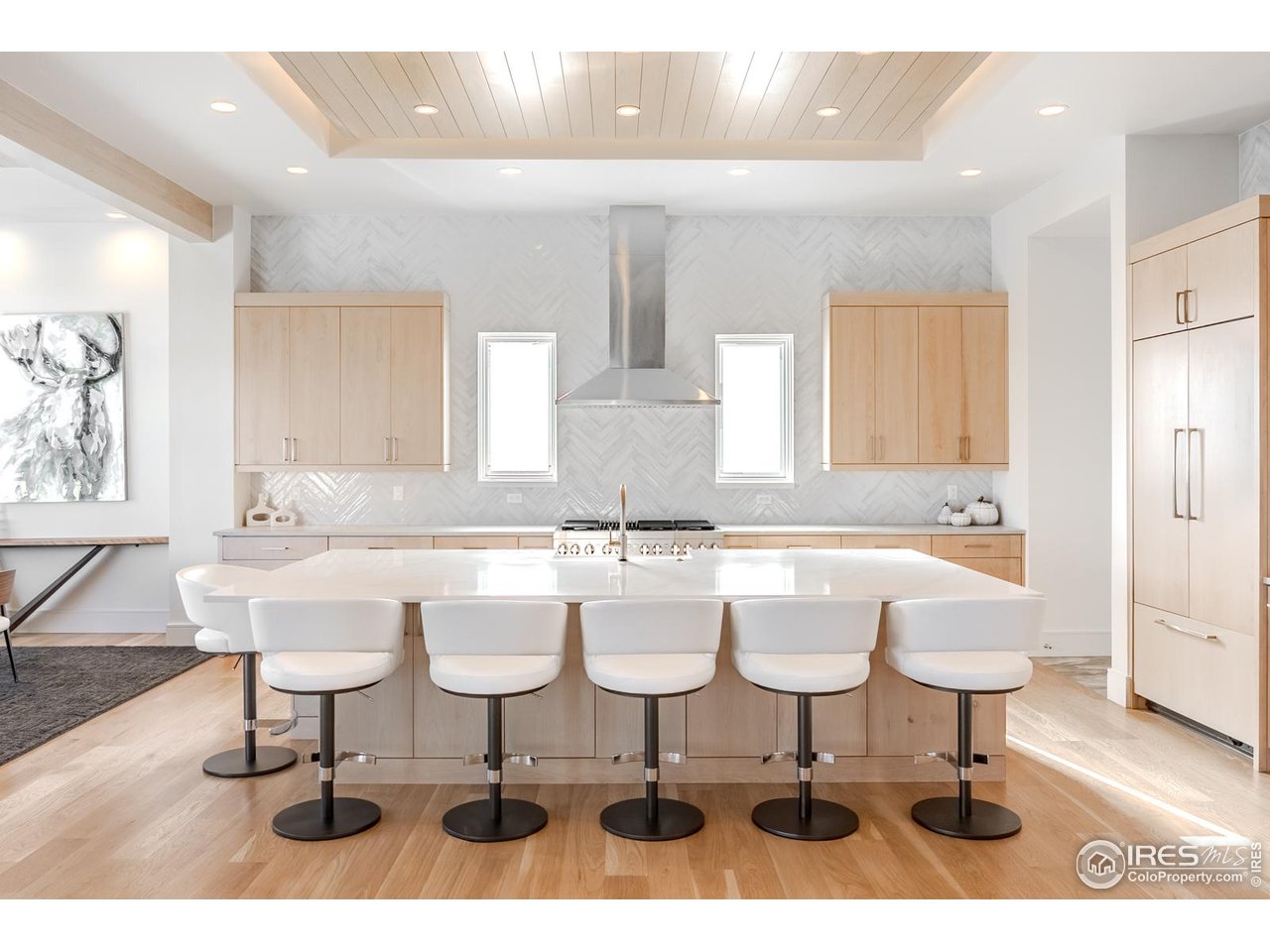 7572 Raphael Lane Littleton, CO 80125 - Photo 6 of 50 A floating white-oak drop ceiling glows with concealed lighting, hovering above an eleven foot quartz island seating six- an inviting center for connection and effortless entertaining.