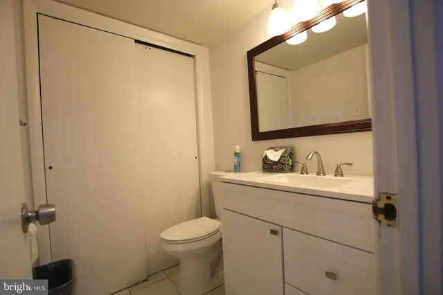 a bathroom with a granite countertop sink vanity mirror and toilet