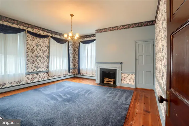 a view of an empty room with window fireplace and wooden floor
