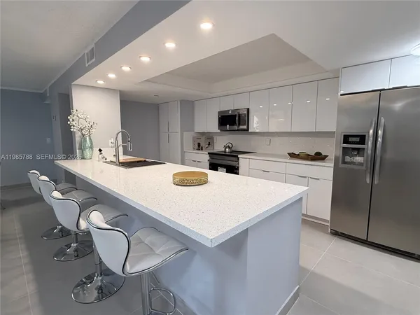 a kitchen with kitchen island a white counter top space stainless steel appliances and cabinets
