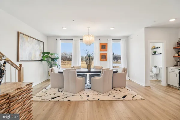 a kitchen with stainless steel appliances a dining table chairs and couches with wooden floor