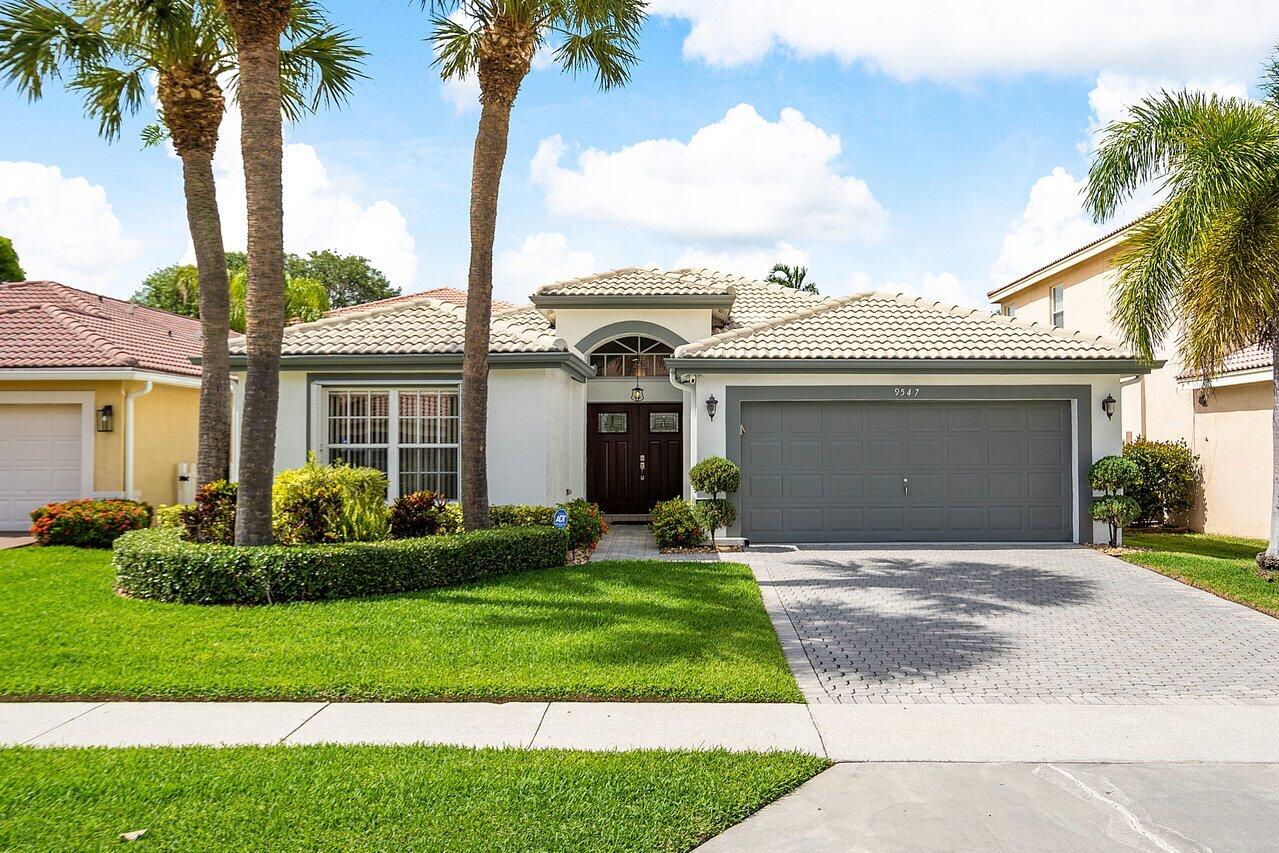 9547 Fox Trot Lane Boca Raton, FL 33496 - Photo 1 of 38 a front view of a house with a garden and yard