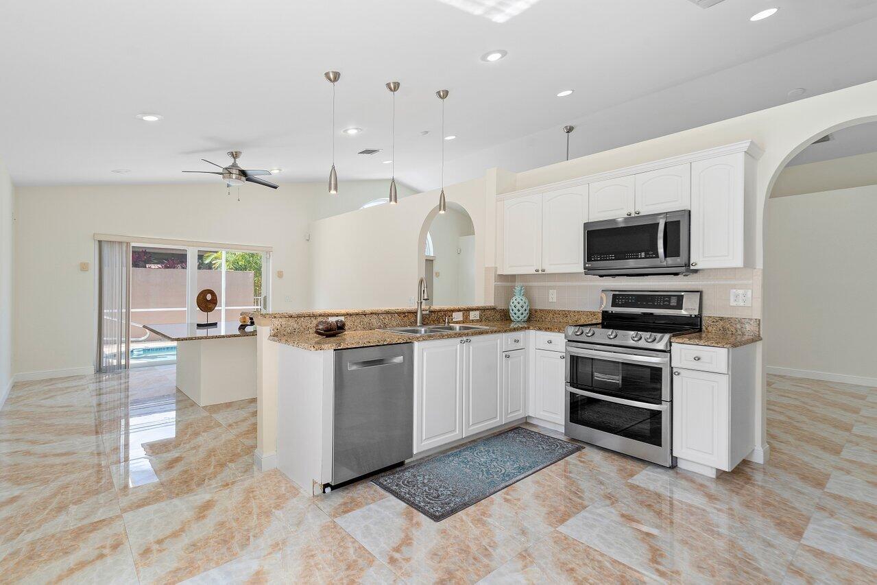 9547 Fox Trot Lane Boca Raton, FL 33496 - Photo 9 of 38 a large white kitchen with sink stove and refrigerator