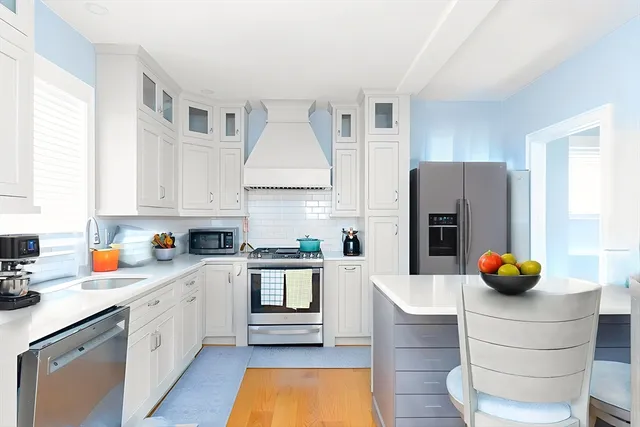 a kitchen with stainless steel appliances a stove a sink and white cabinets