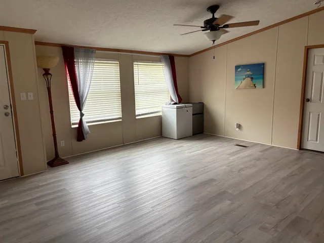 an empty room with wooden floor and windows