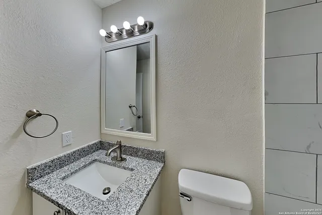 a bathroom with a granite countertop sink and a mirror