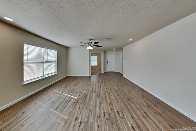 a view of empty room with wooden floor and fan
