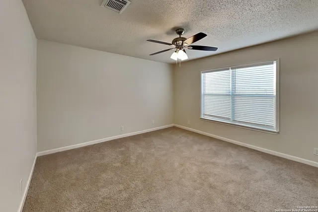 an empty room with a window and a fan